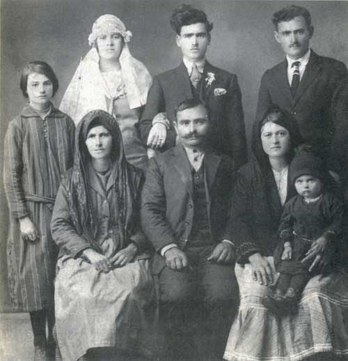 Αναμνηστική νυφική φωτογραφία, όπου ξεχωρίζουν τρεις τύποι αμφίεσης.  Οι καθστές γυναίκες με ντόπια φορέματα, η στολή της νύφης και οι «φραγκοφορεμένοι» άντρες με το γαμπρό.