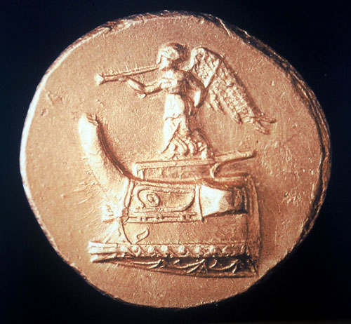 Εικ. 13. Νίκη με σάλπιγγα σε χρυσό στατήρα Δημητρίου του Πολιορκητού. (Θησαυρός Επιδαύρου) του 300 π.Χ. περίπου. Νομισματικό Μουσείο Αθηνών.